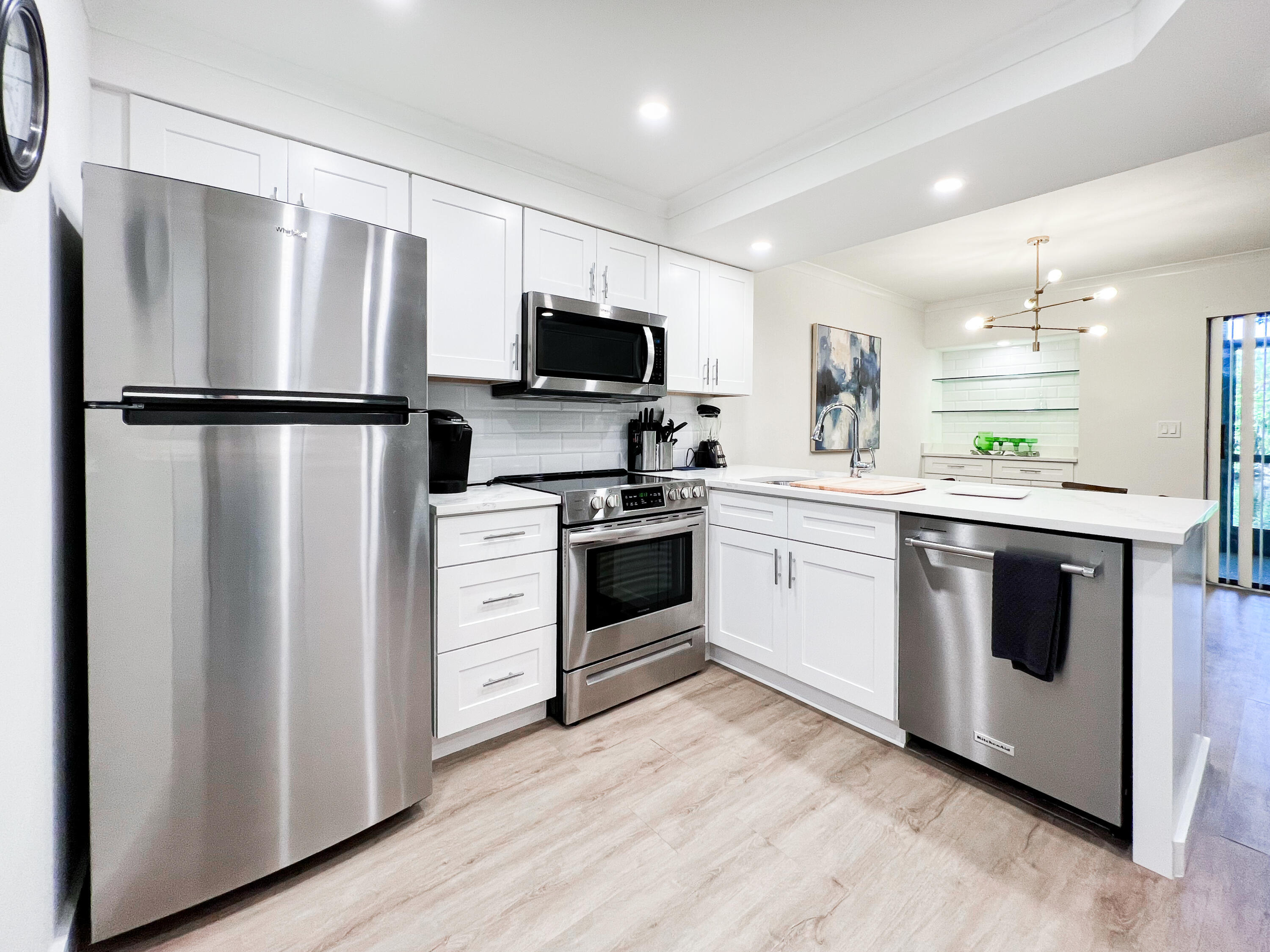 1605 Highway 1, Unit C103 Jupiter, FL 33477 - Photo 3 of 26 a kitchen with white cabinets and stainless steel appliances