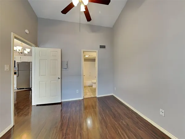 an empty room with wooden floor and a ceiling fan