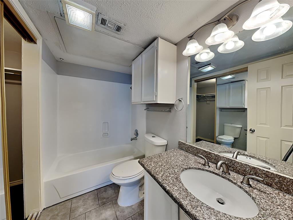 6108 Abrams Road, Unit 323 Dallas, TX 75231 - Photo 6 of 7 a bathroom with a granite countertop sink a toilet a mirror and bathtub