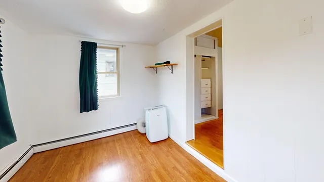 a view of empty room with wooden floor and ceiling fan