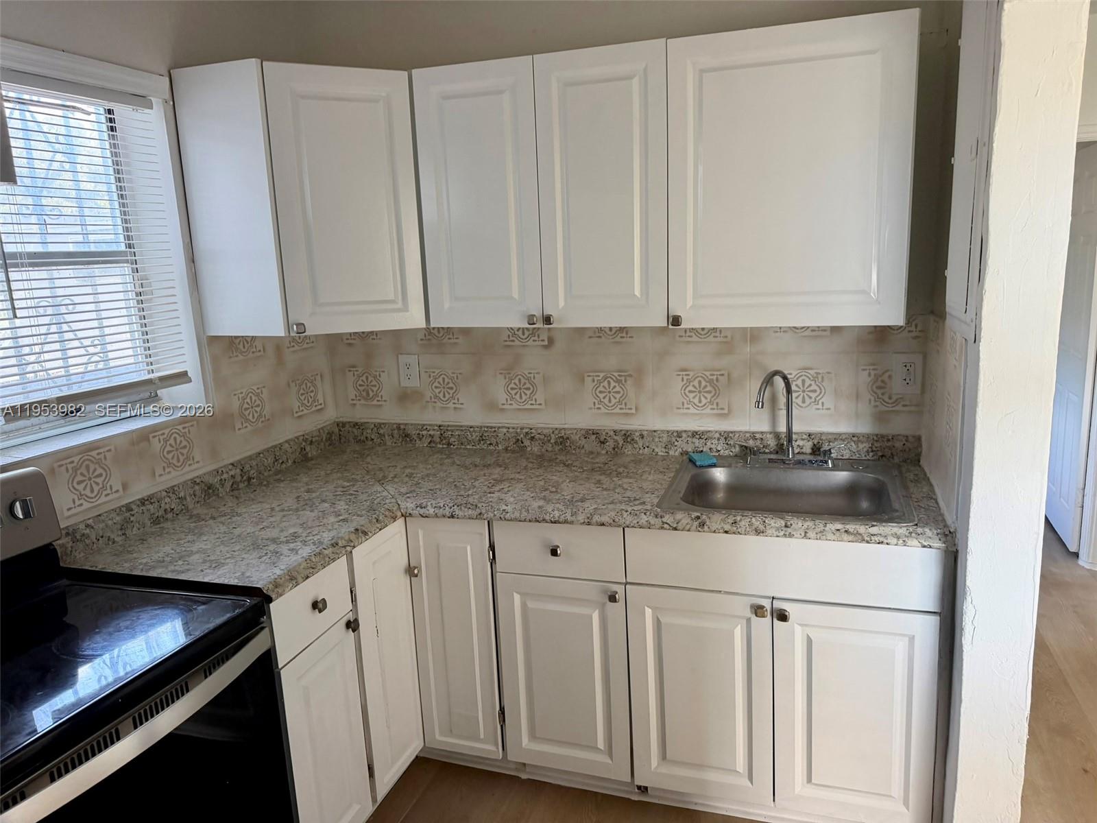 413 Northwest 63rd Street Miami, FL 33150 - Photo 31 of 55 a kitchen with stainless steel appliances granite countertop a sink and dishwasher with white cabinets