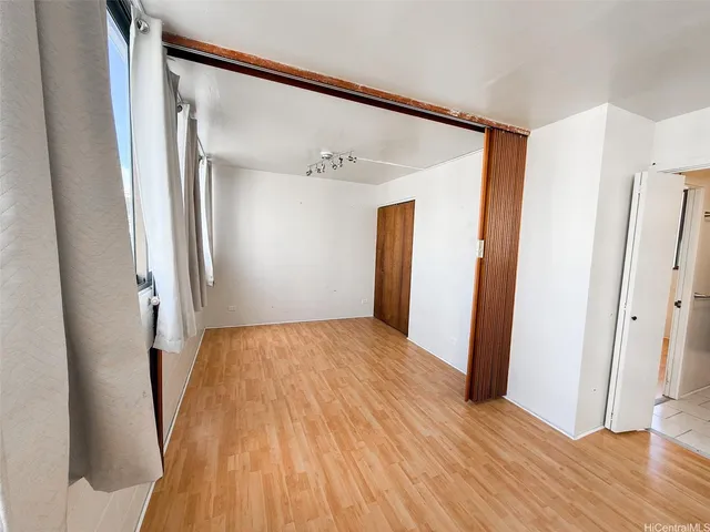 a view of an empty room with wooden floor and a bathroom