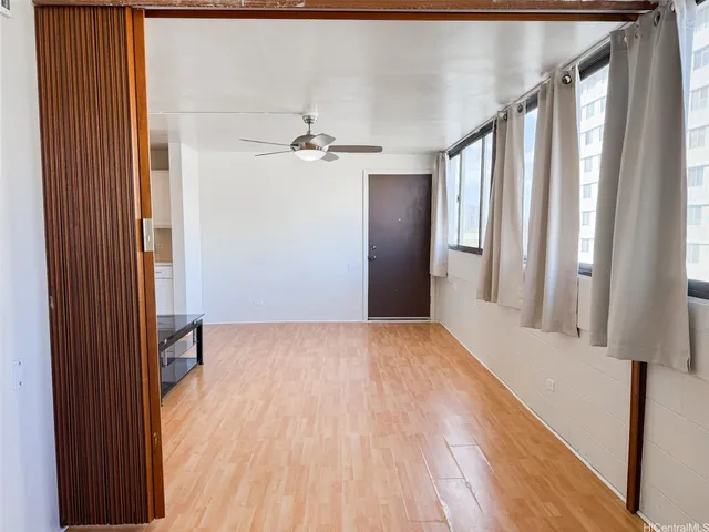 a view of an empty room with wooden floor and a window