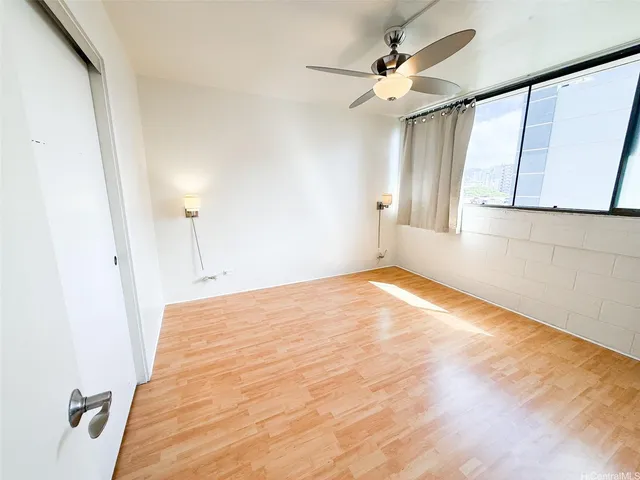 a view of empty room with wooden floor and fan