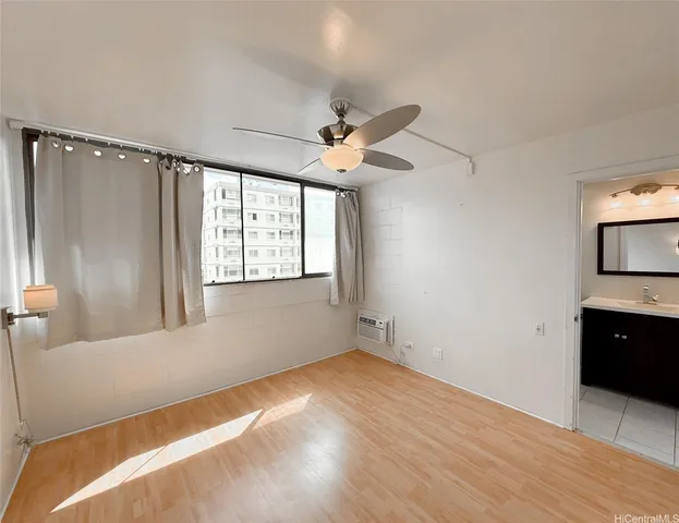 a view of empty room with wooden floor and fan
