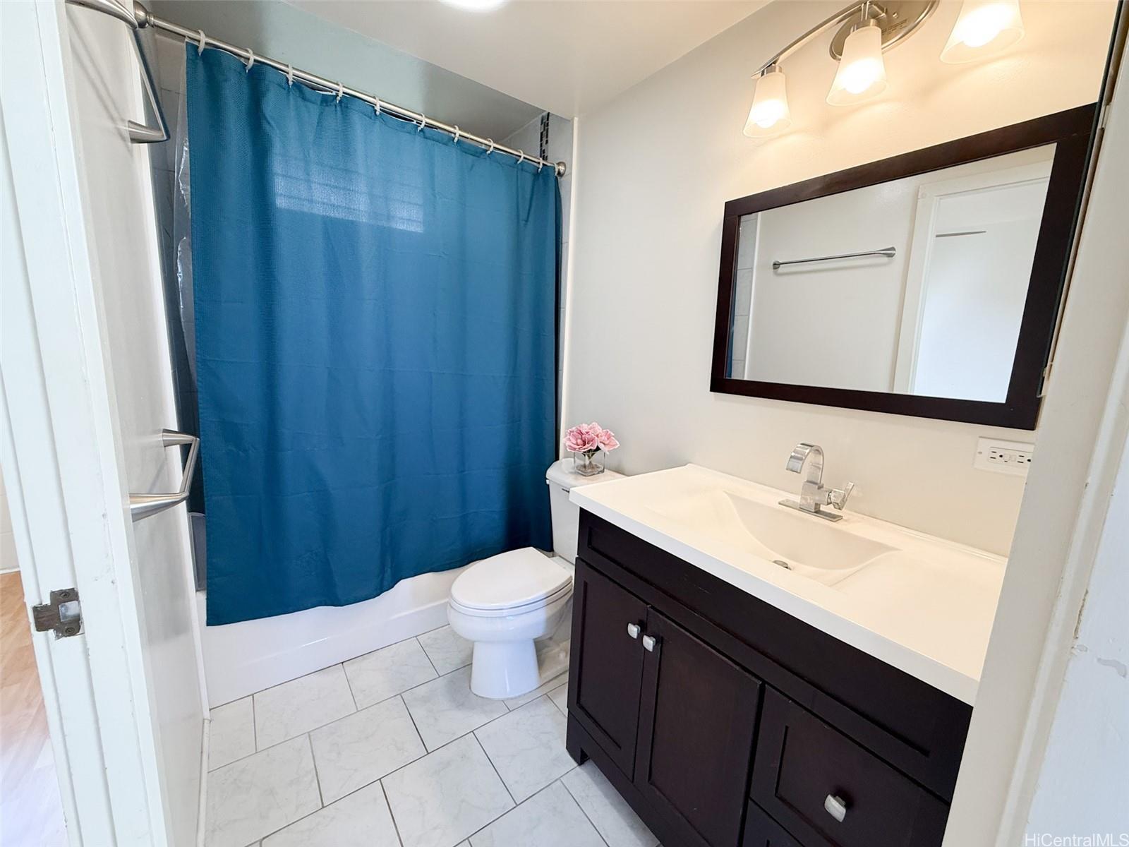 1134 Kinau Street, Unit 607 Honolulu, HI 96814 - Photo 8 of 10 a bathroom with a sink a toilet a mirror and shower curtain
