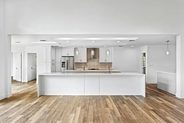 a large white kitchen with a sink and dishwasher a stove with wooden floor