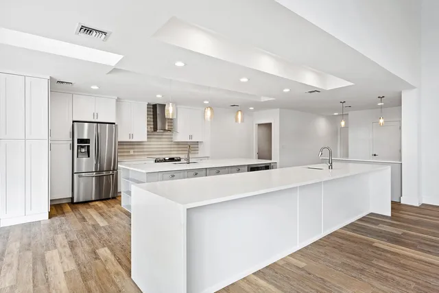 a large white kitchen with kitchen island a sink a stove a refrigerator and a cabinets