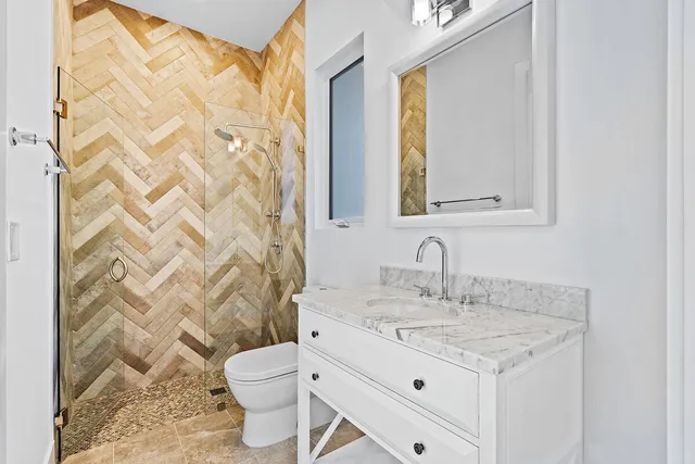 a bathroom with a granite countertop sink a toilet and a mirror