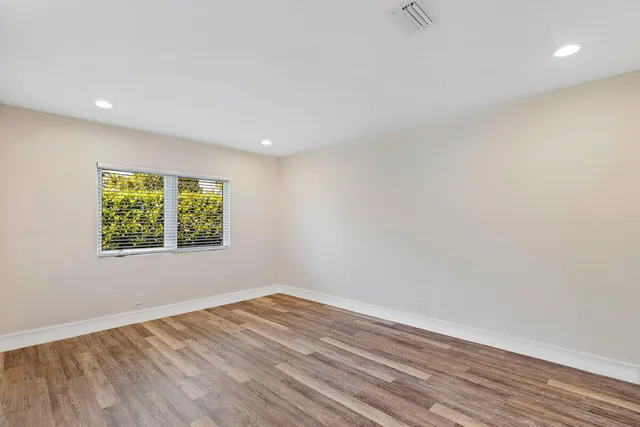a view of an empty room with wooden floor and a window
