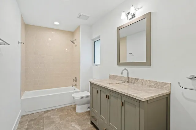 a bathroom with a granite countertop sink a toilet and a mirror