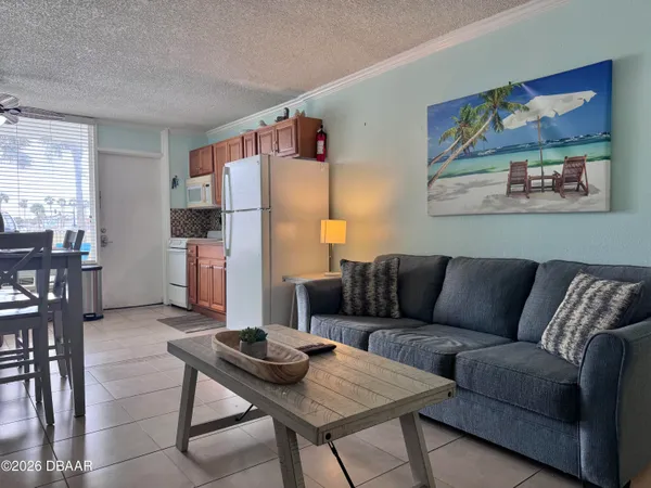 a living room with furniture and a refrigerator