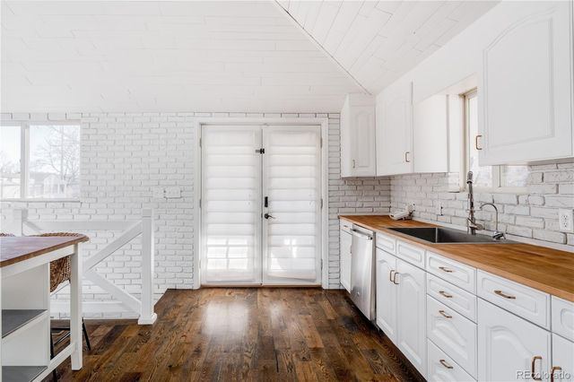 a kitchen with stainless steel appliances granite countertop a stove top oven a refrigerator a sink and chairs