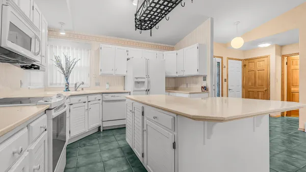 a kitchen with white cabinets appliances a sink and a window