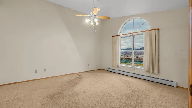 an empty room with a chandelier fan and windows