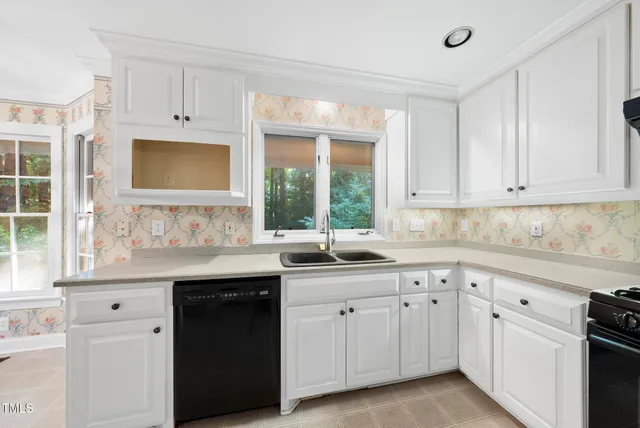 a kitchen with white cabinets and window
