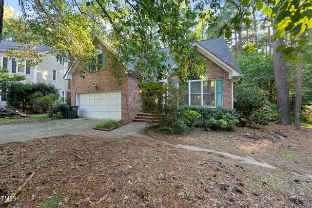 a front view of a house with a yard and a tree