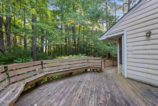 a view of a wooden deck with a bench and trees