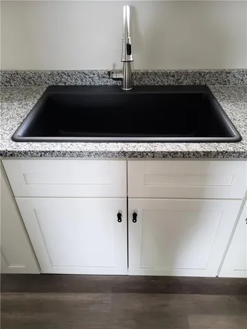 a kitchen with granite countertop white cabinets and black appliances