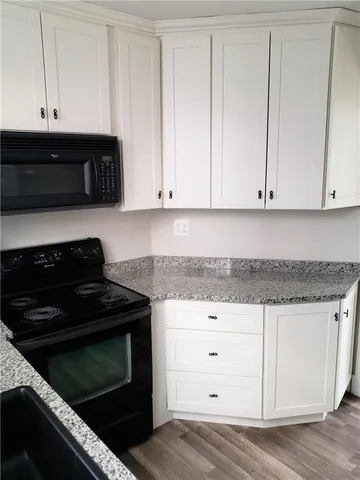a kitchen with granite countertop white cabinets and stainless steel appliances