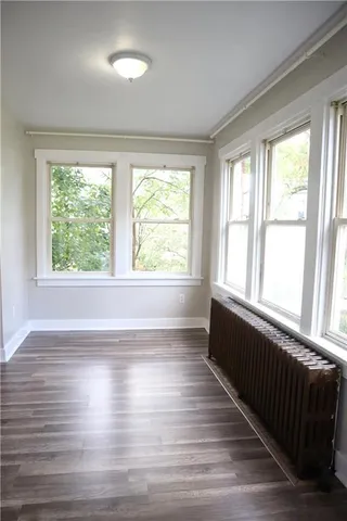 a view of an empty room with wooden floor and a window