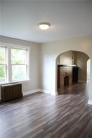 an empty room with wooden floor fireplace and windows