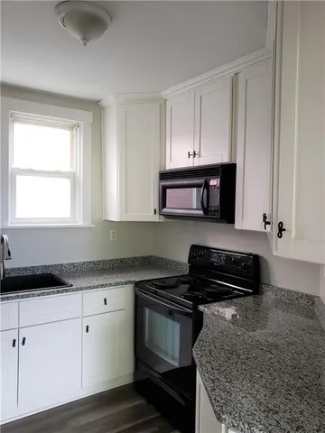 a kitchen with granite countertop white cabinets and black appliances