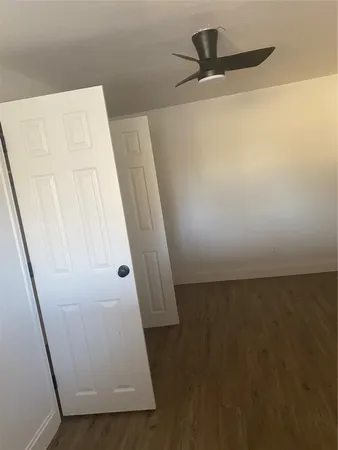 a view of an empty room with wooden floor and windows