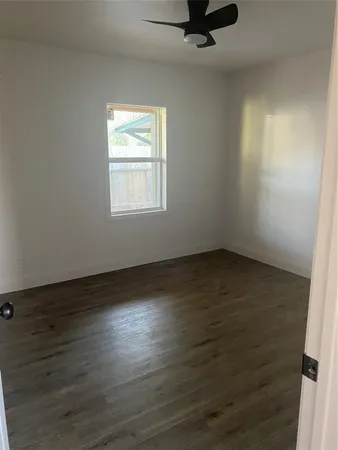 an empty room with wooden floor cabinet and windows