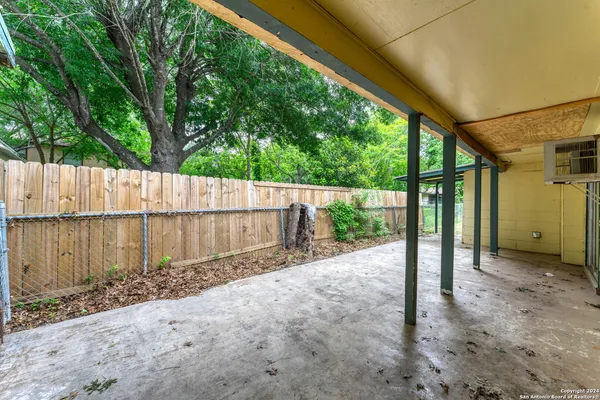 a view of a backyard with wooden fence and large trees