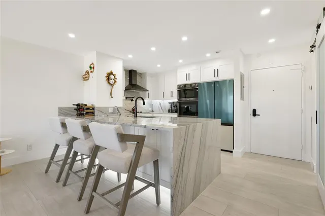 a kitchen with stainless steel appliances kitchen island granite countertop a dining table chairs and a refrigerator