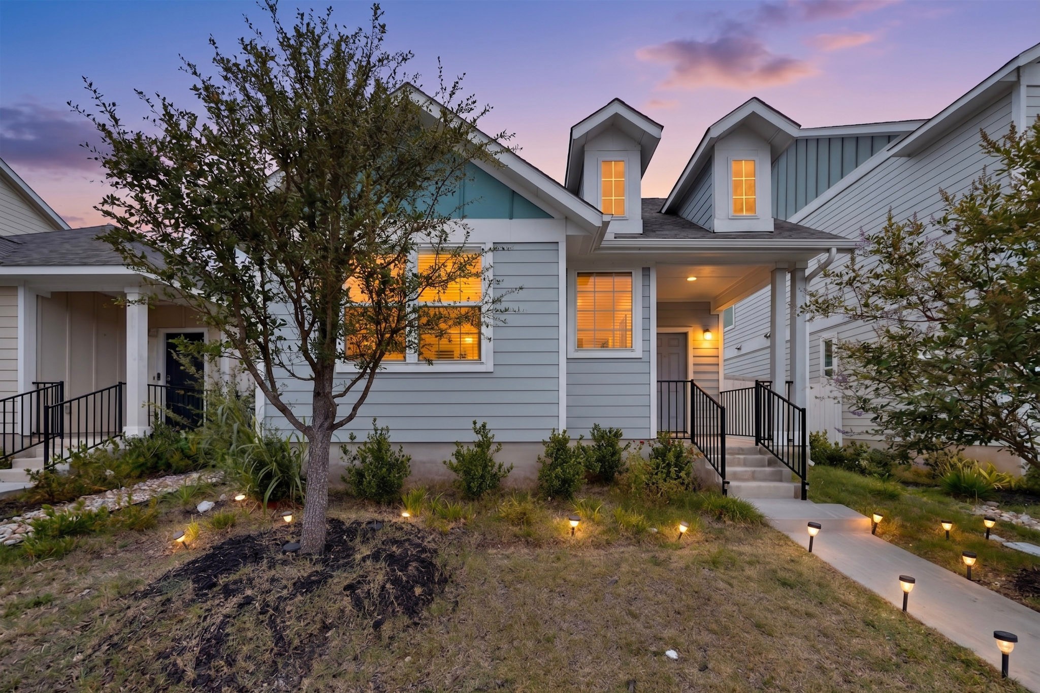 116 Appleberry Lane Elgin, TX 78621 - Photo 1 of 35 A welcoming facade with a covered entry and dormer windows, illuminated by evening lights.