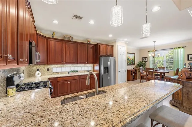 a kitchen with stainless steel appliances kitchen island granite countertop a stove refrigerator and cabinets