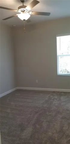 a view of an empty room with window and chandelier fan