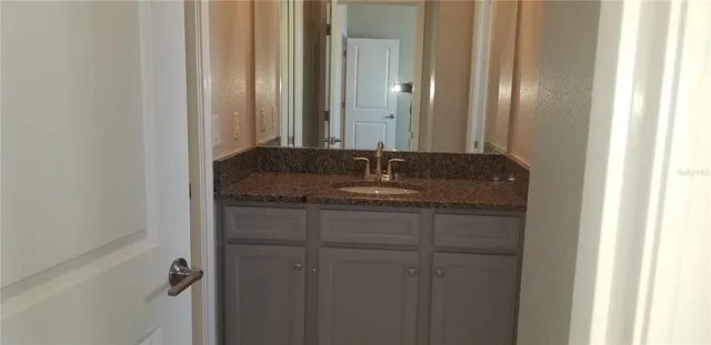 a bathroom with a granite countertop sink and a mirror