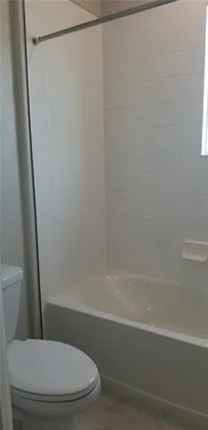 a white toilet sitting next to a bath tub