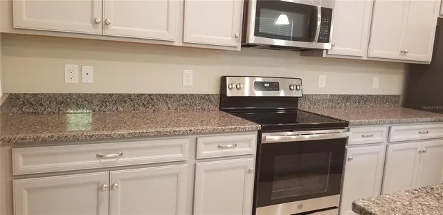 a kitchen with granite countertop white cabinets and a stove