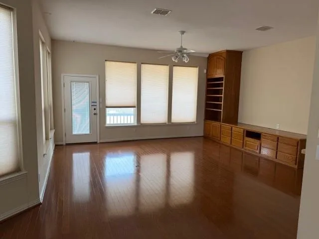 an empty room with wooden floor and windows