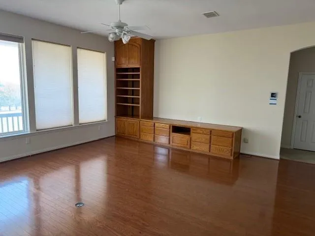 an empty room with wooden floor and windows
