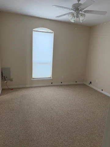 an empty room with a fan & a window