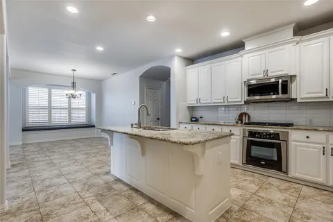 a kitchen with kitchen island granite countertop a stove sink and microwave