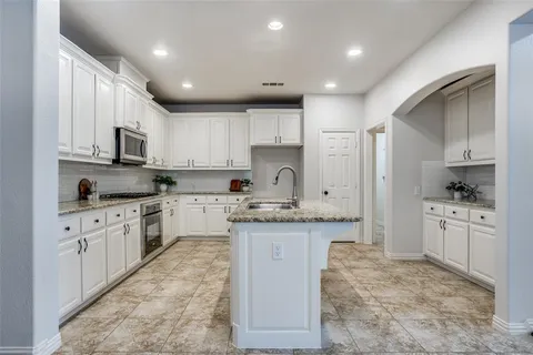 a kitchen with granite countertop a sink stove cabinets and refrigerator