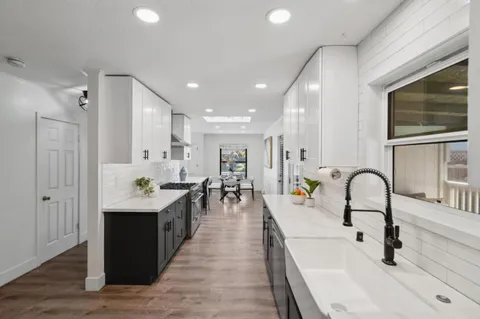 a dining hall with stainless steel appliances granite countertop a sink a stove and wooden floors