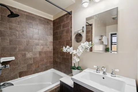 a bathroom with a sink and mirror with bathtub