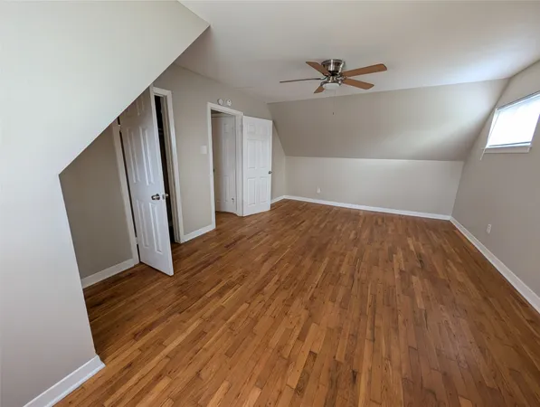 an empty room with wooden floor and a ceiling fan