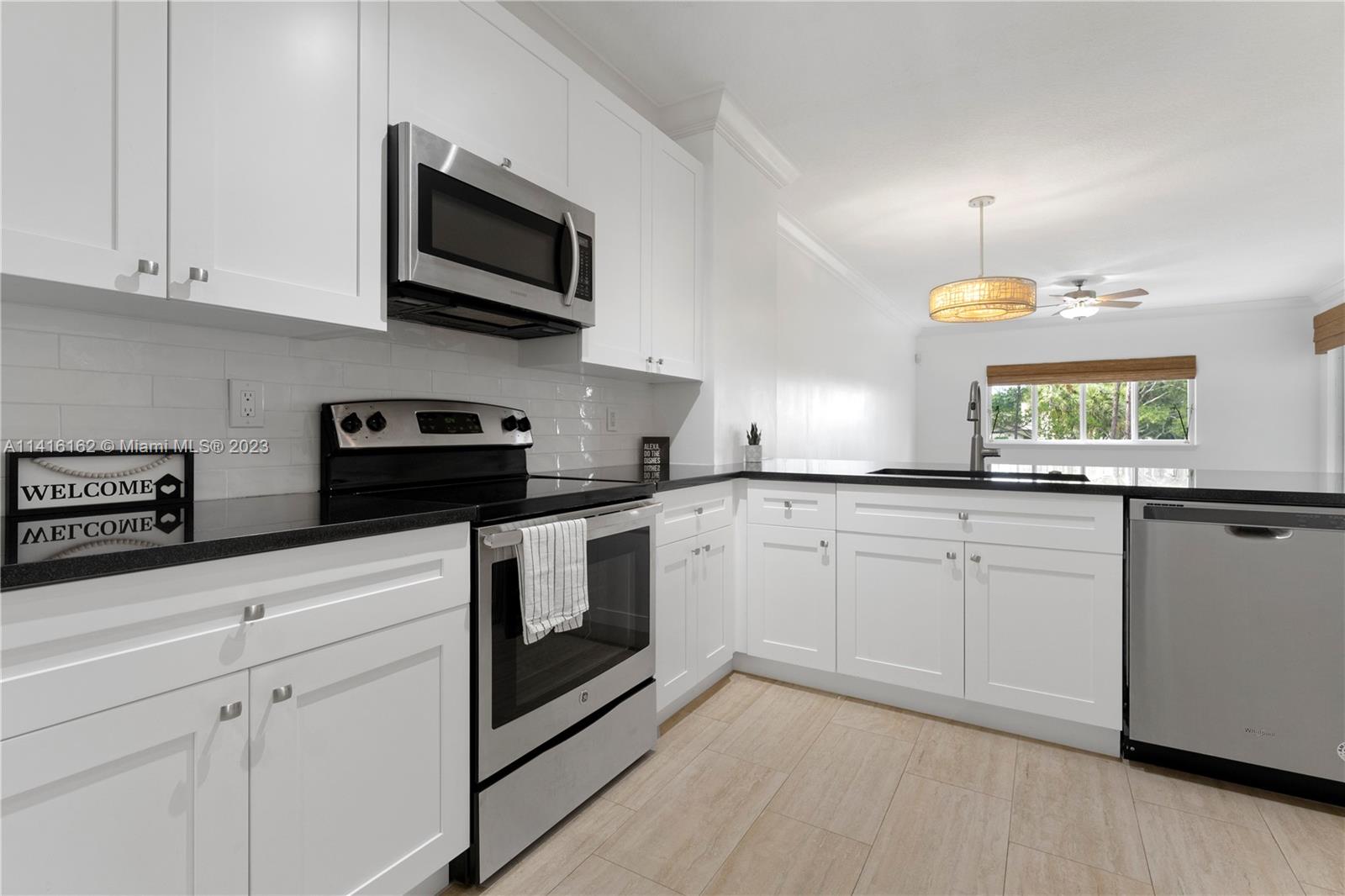 22701 Camino Del Mar, Unit 25 Boca Raton, FL 33433 - Photo 4 of 19 a kitchen with white cabinets stainless steel appliances and sink
