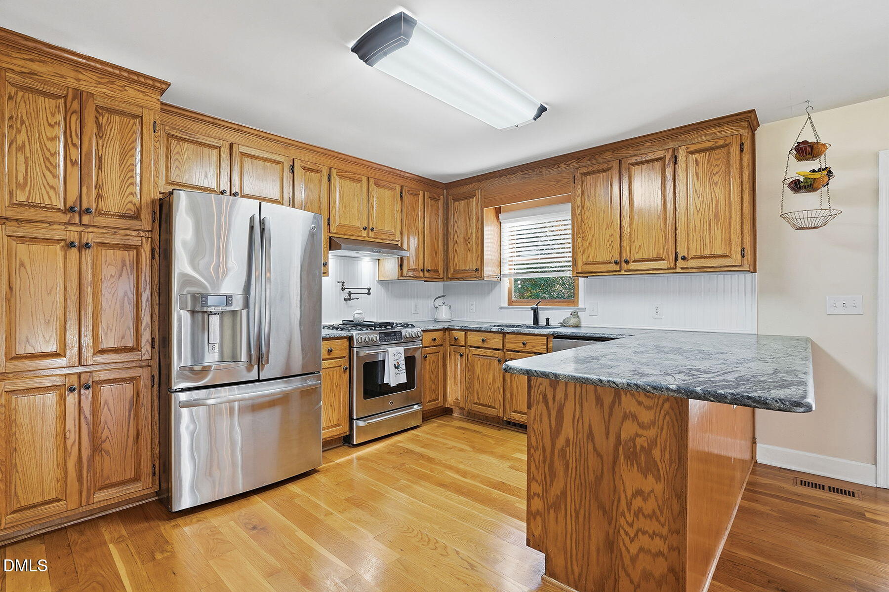 229 Plantation Road Clayton, NC 27520 - Photo 10 of 32 a kitchen with granite countertop stainless steel appliances a refrigerator cabinets and wooden floor