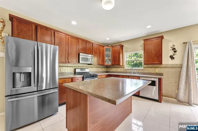 a kitchen with stainless steel appliances granite countertop a refrigerator a stove a sink and a microwave