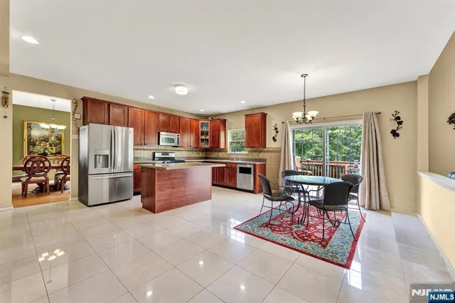 a kitchen with stainless steel appliances kitchen island granite countertop a refrigerator oven stove a sink a dining table and chairs with wooden floor