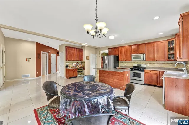 a open kitchen with stainless steel appliances granite countertop a stove a sink a dining table and chairs